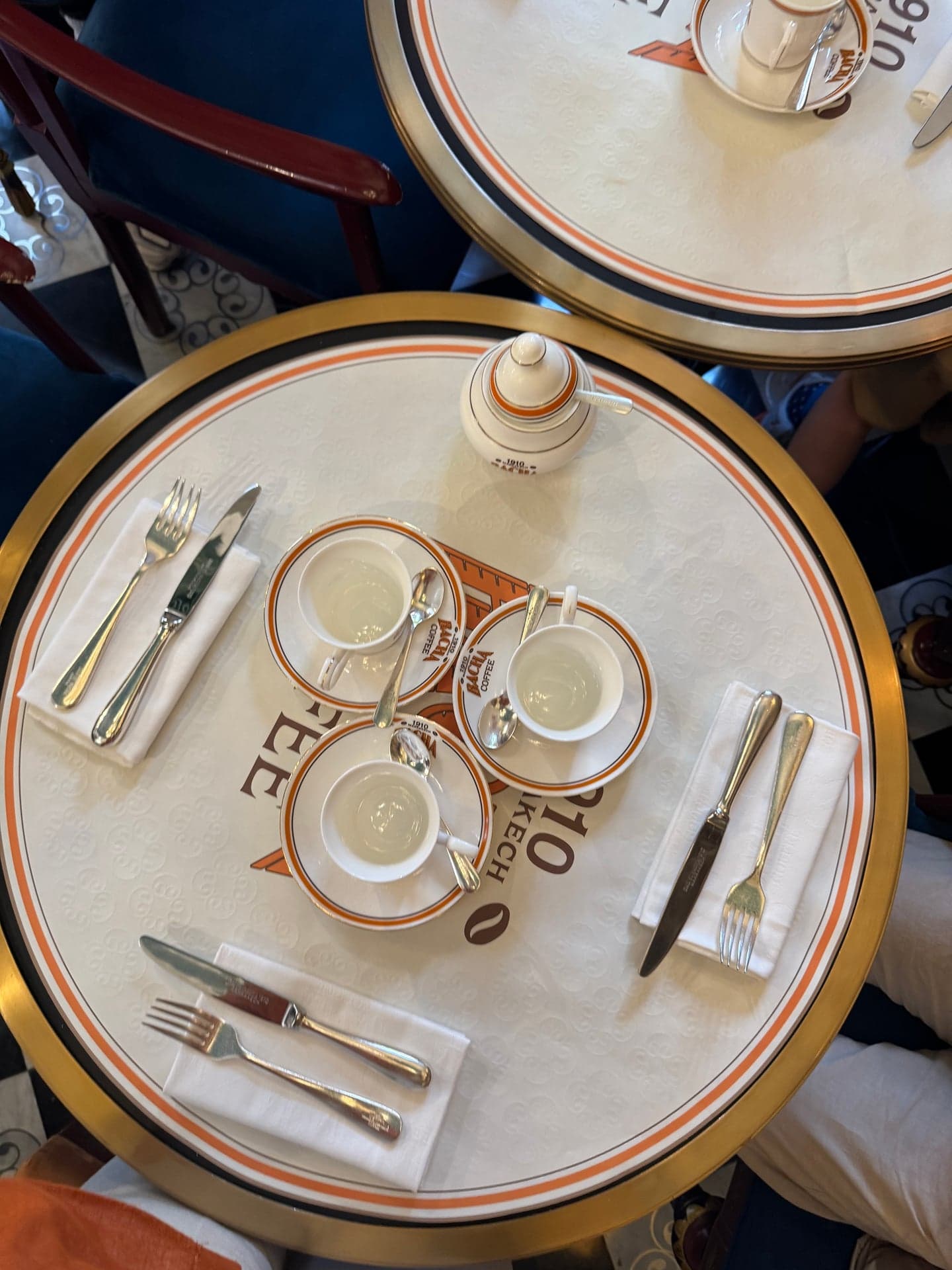 Top-down: three Bacha cups on a round table set with cutlery and napkins